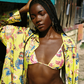 Woman in a colorful yellow bikini and floral cover-up standing outdoors.