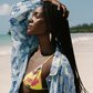 Woman in a floral yellow bikini and blue cover-up on a beach