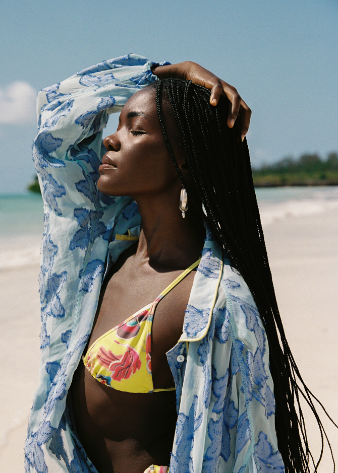 Woman in a floral yellow bikini and blue cover-up on a beach