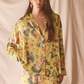 Woman wearing a yellow floral pajama set against a beige background