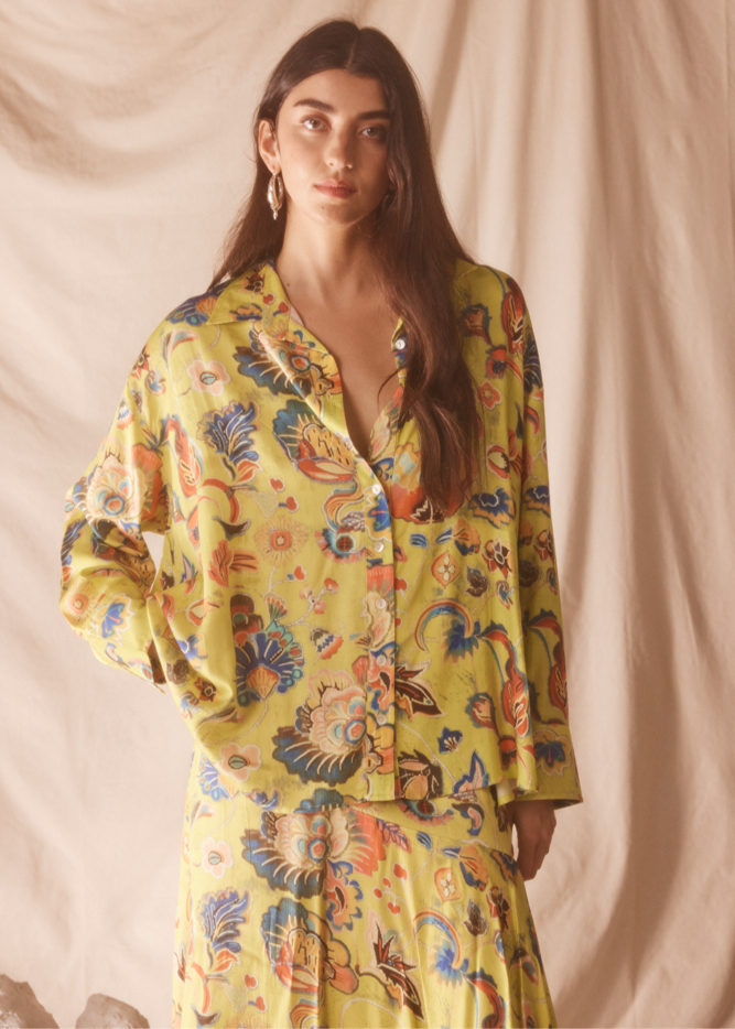 Woman wearing a yellow floral pajama set against a beige background