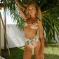 Woman in a colorful yellow bikini standing under palm trees