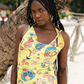 Woman wearing a colorful yellow floral dress standing under a tree