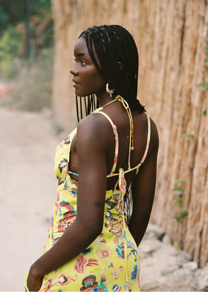 Woman in a colorful yellow dress standing outdoors with a natural background