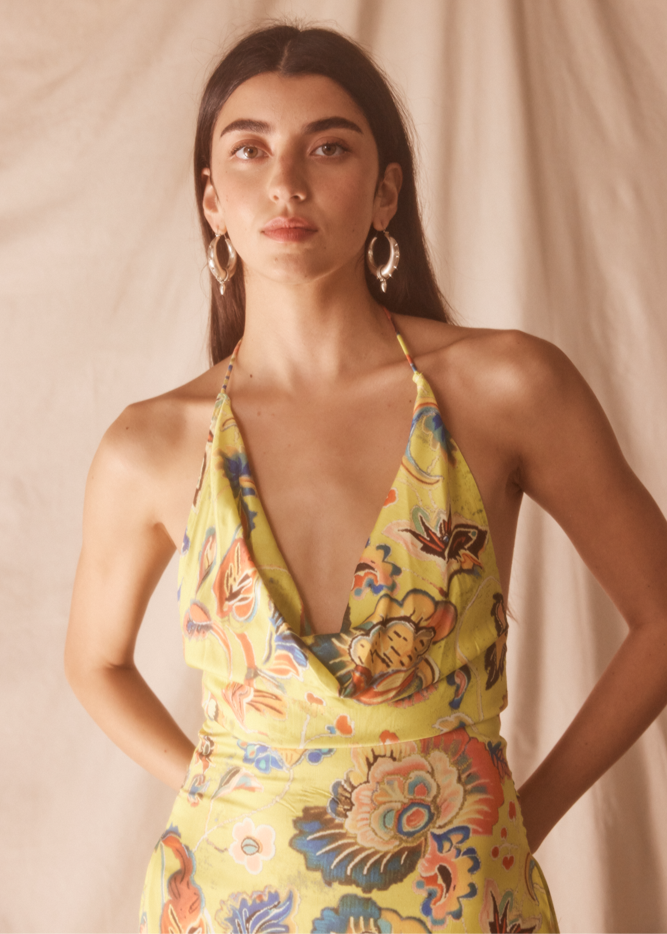 Woman wearing a yellow floral dress against a beige background