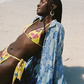 Woman in a yellow bikini and blue floral cover-up on a beach