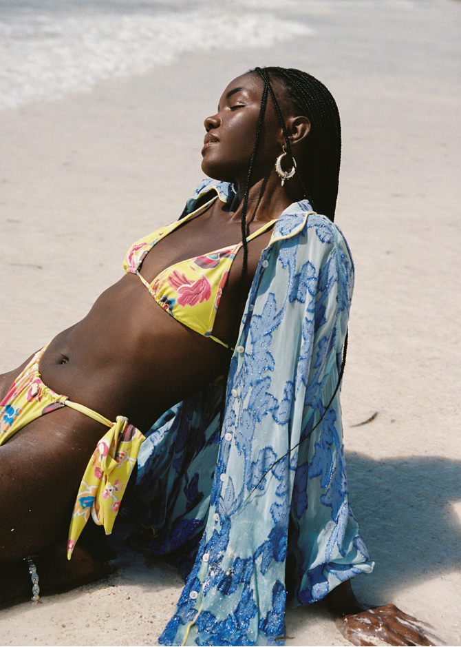 Woman in a yellow bikini and blue floral cover-up on a beach