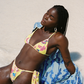 Woman in a yellow floral bikini and blue cover-up on a sandy beach
