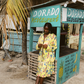 Woman in a yellow floral set standing in front of a Dorado Restaurant stand.