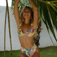 Woman in a colorful yellow floral bikini standing under a palm tree