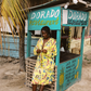 Woman in a yellow set standing in front of a Dorado Restaurant sign.