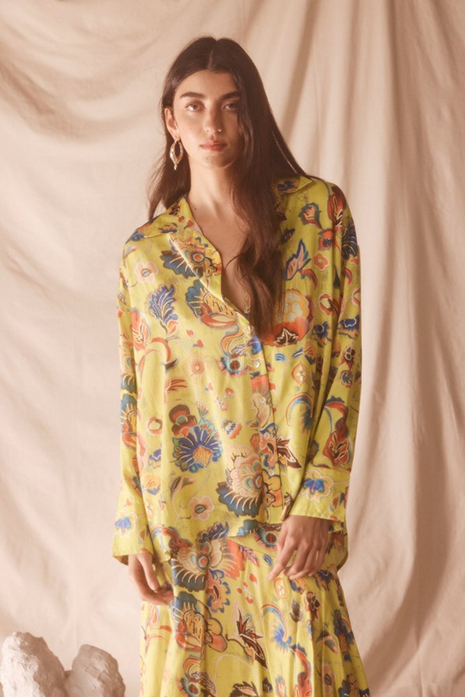 Woman wearing a yellow floral set against a beige background