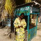 Woman in a yellow floral set standing in front of a Dorado restaurant stand.
