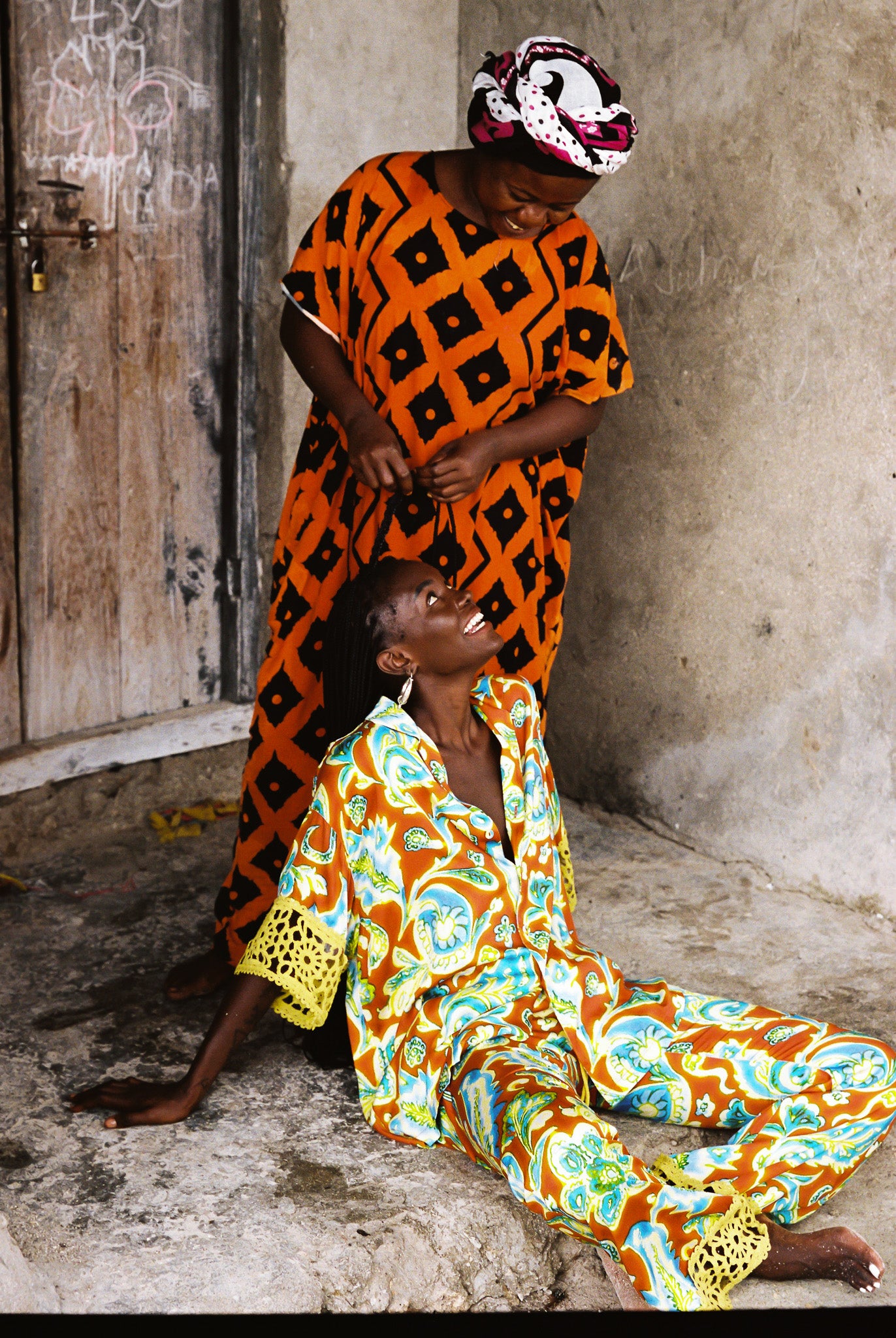 Woman wearing orange, blue and green patterned shirt and flared pant set with lime green embroided trim.