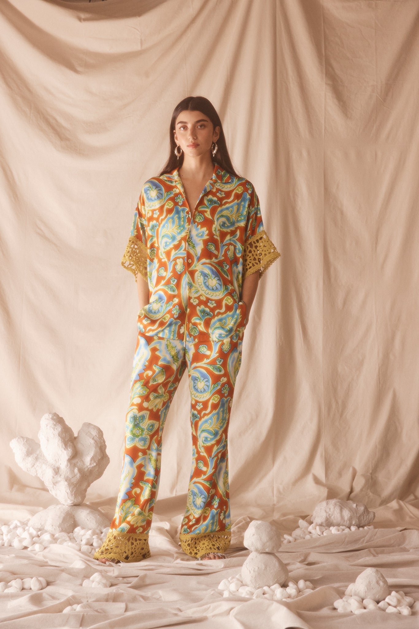 Woman wearing orange, blue and green patterned shirt and flared pant set with lime green embroided trim.