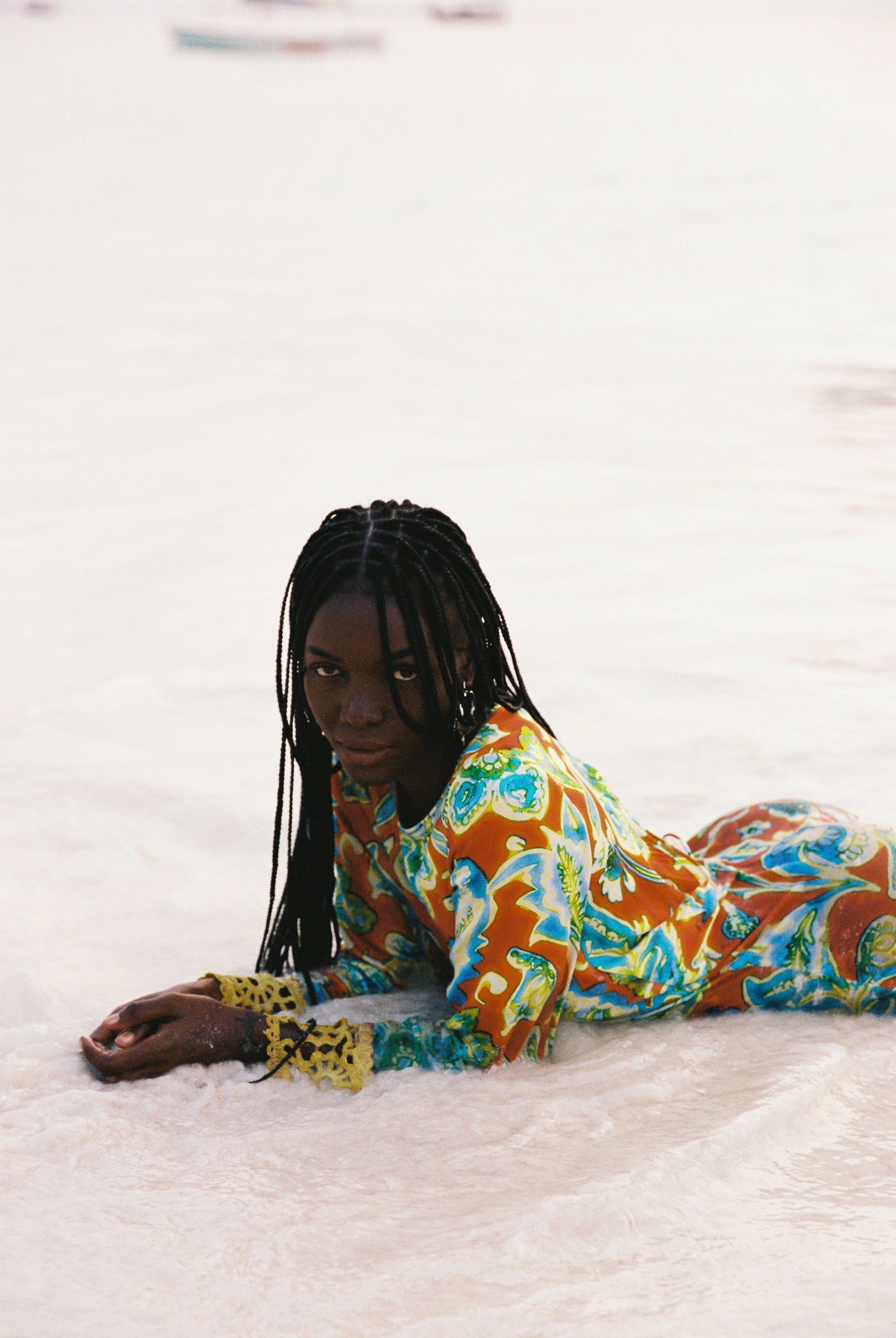 Woman wearing a colorful orange, blue and green patterned dress with lime green embroided contrast trim detail