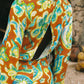 Woman wearing a colorful orange, blue and green patterned dress with lime green embroided contrast trim detail