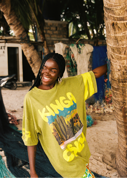 Woman wearing a bright lime green t-shirt with desert text and graphics, standing outdoors near trees.