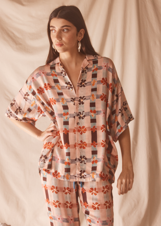 Woman wearing a pink patterned outfit against a plain background