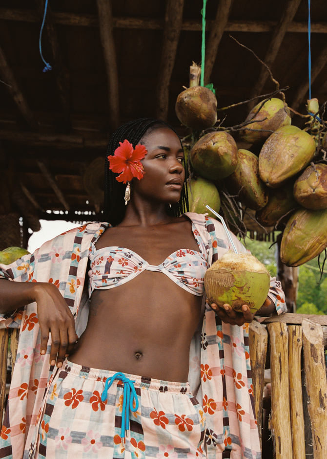 Woman holding a coconut wearing pink patterned set and matching bikini top.