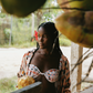 Woman in a tropical setting holding coconuts wearing matching pink patterned set and bikini top