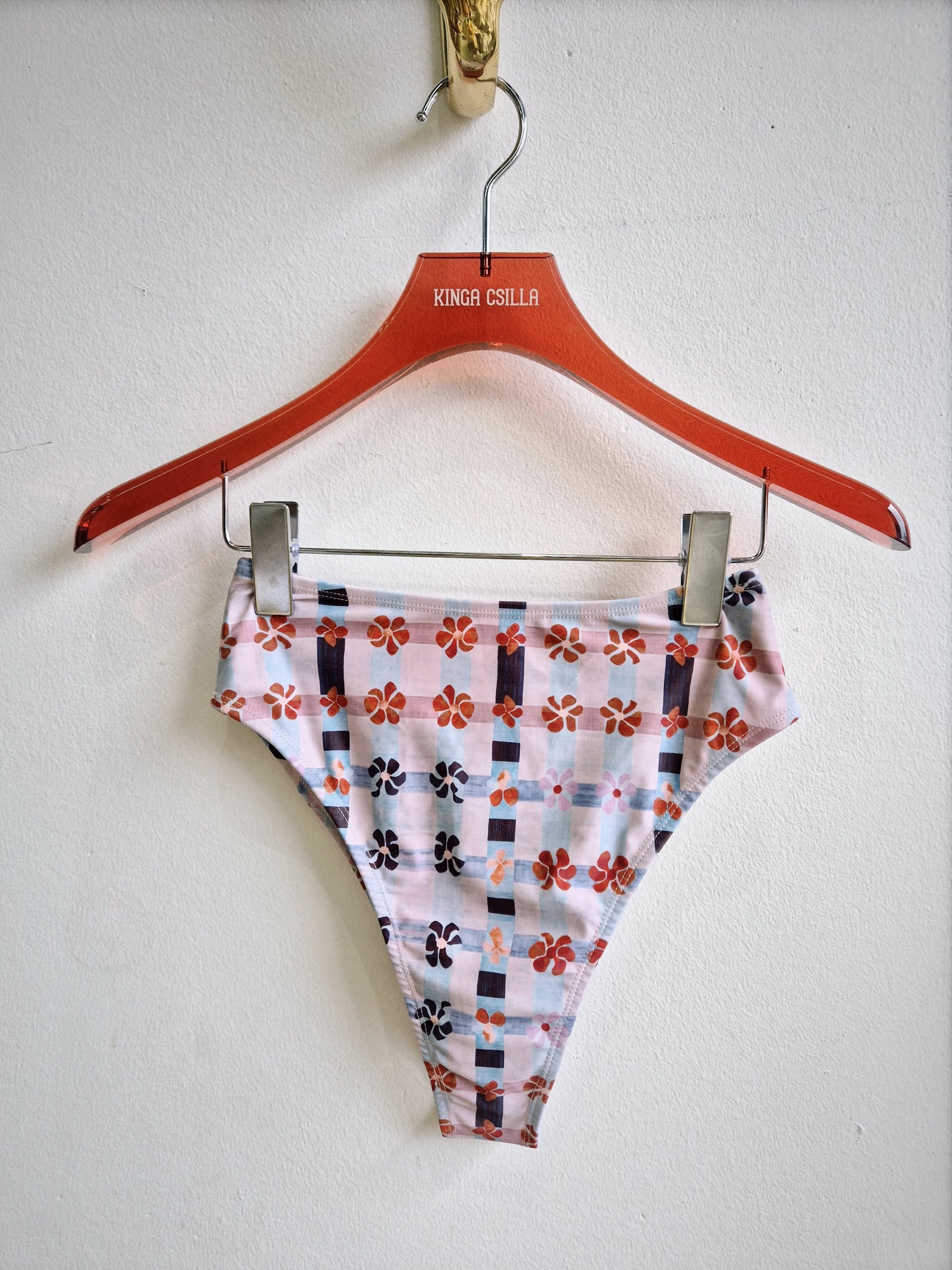 Pink floral-patterned high-waisted bikini bottom on a hanger against a white background