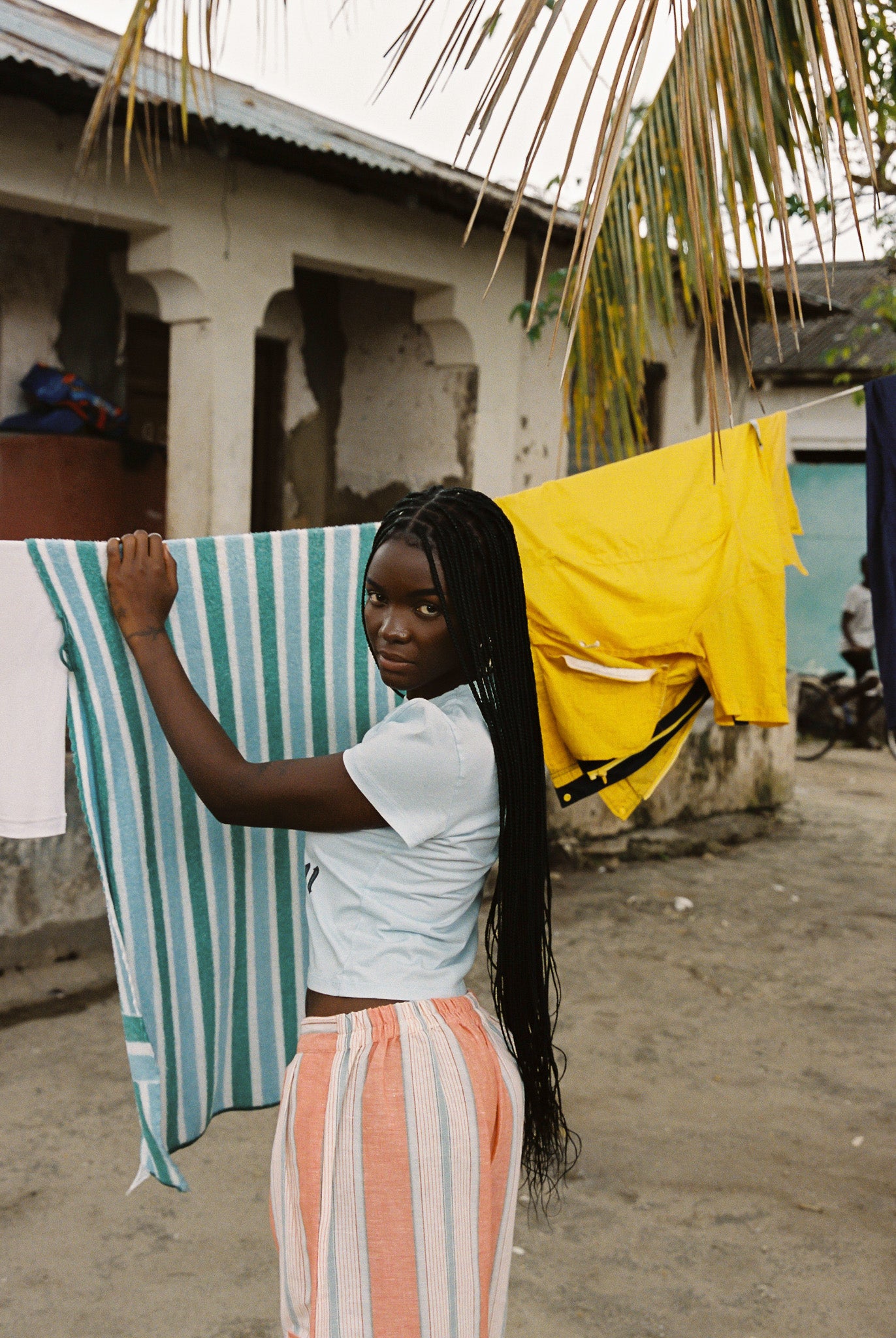 Woman wearing linen-cotton wide leg pants in peach, blue and ivory coastal stripes with side pockets and elastic waistband.