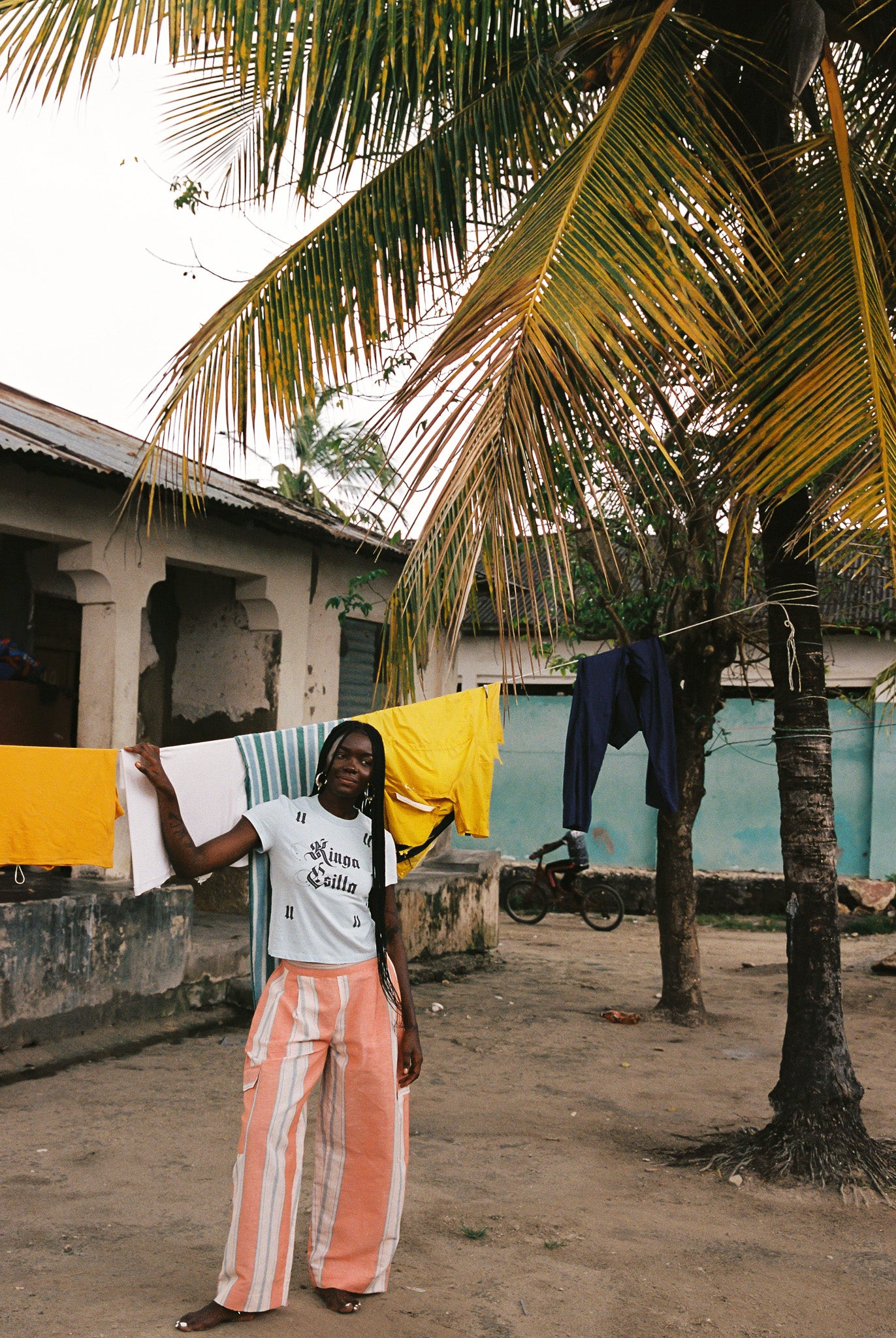 Woman wearing linen-cotton wide leg pants in peach, blue and ivory coastal stripes with side pockets and elastic waistband.