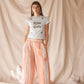 Woman wearing linen-cotton wide leg pants in peach, blue and ivory coastal stripes with side pockets and elastic waistband.