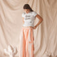 Woman wearing linen-cotton wide leg pants in peach, blue and ivory coastal stripes with side pockets and elastic waistband.