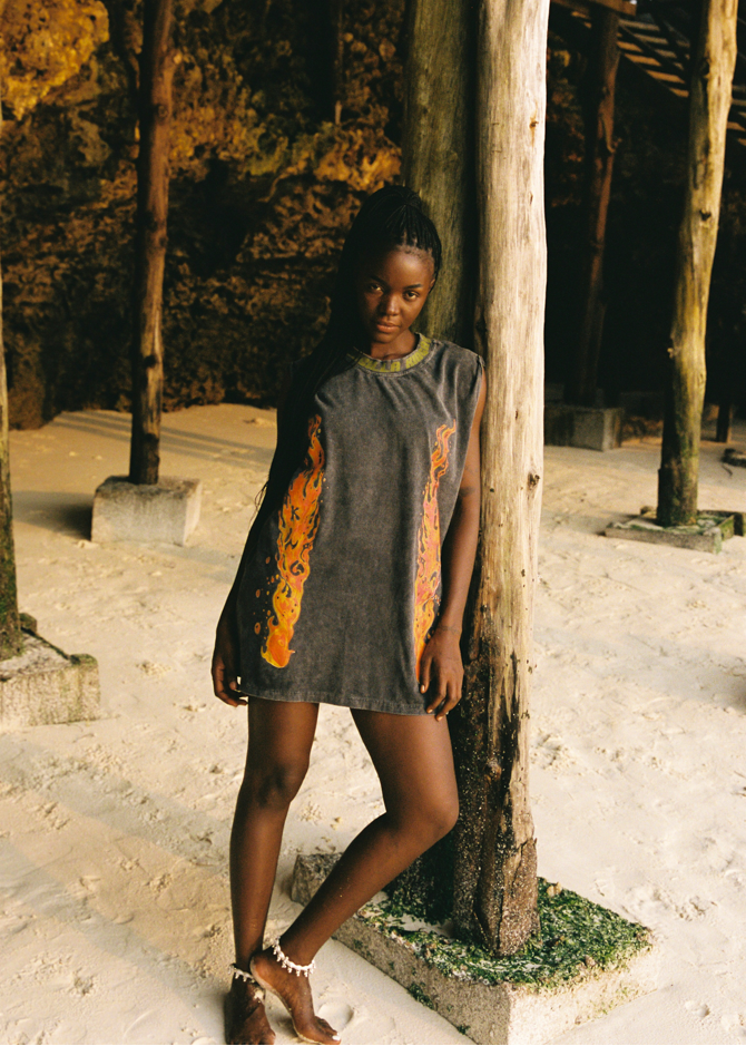 Woman in a sleeveless tank with flame graphics standing next to a wooden post in a natural setting