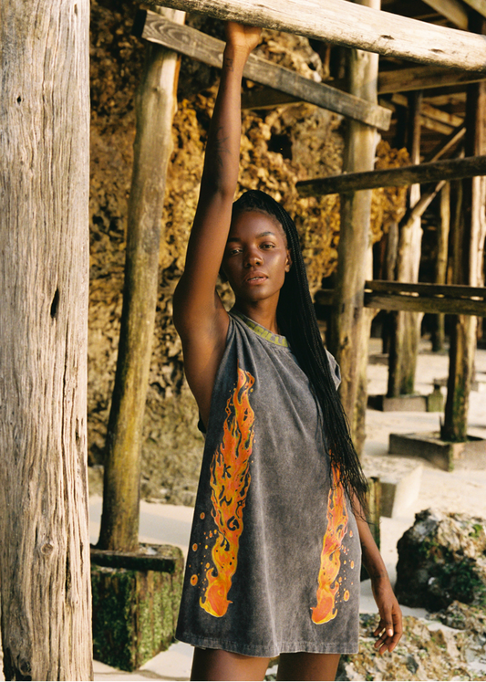 Woman in a sleeveless shirt tank with orange flame patterns standing near wooden structures.