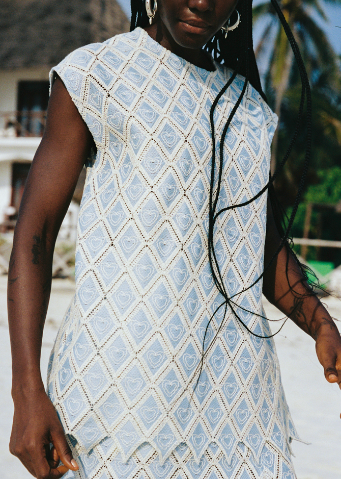 Person wearing a light blue patterned set with palm trees in the background