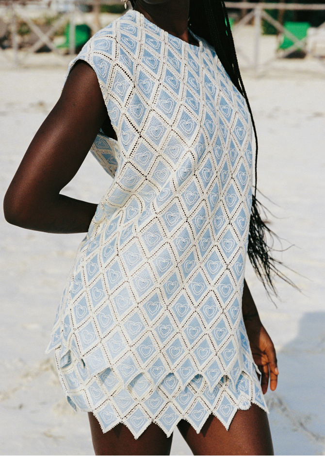 Person wearing a light blue patterned set on a beach.