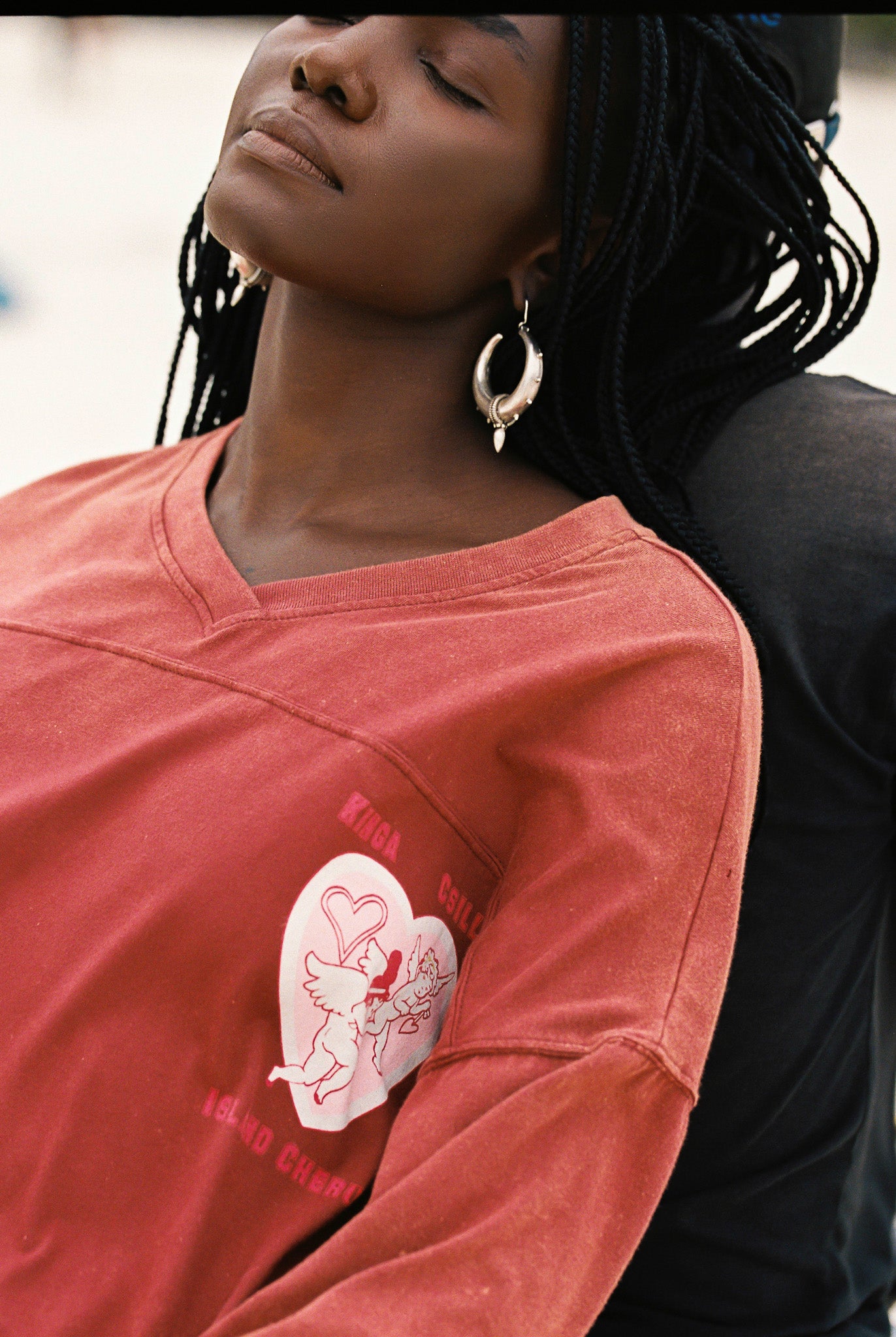 Person wearing a red shirt dress with a pink and white graphic design on the sleeve.