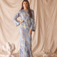 Woman wearing semi-sheer blue maxi with gold lurex florals, flared sleeves, and contrast piping.