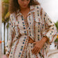 Woman wearing vintage-inspired abstract print in earthy tones; relaxed collared shirt and high-waisted boxer shorts for effortless coastal cool.