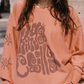 Close-up of Kinga Csilla Abracadabra OG Jumper in terracotta orange with oversized psychedelic logo print and sun motif on sleeve