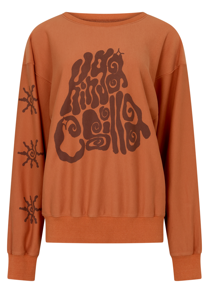 Kinga Csilla Abracadabra OG Jumper in warm orange with oversized fit, KC graphic print across chest and swirly sun motifs on sleeve