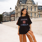 Model wearing Kinga Csilla Bello Swirl Jessi Pant in orange with white embroidery, styled with oversized Kinga Csilla Sunset tee in Paris street style setting