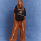 Model wearing Kinga Csilla oversized Sunset t-shirt in black with burnt orange stripe detail, styled with wide leg Bello Swirl Jessi Pant featuring white embroidery