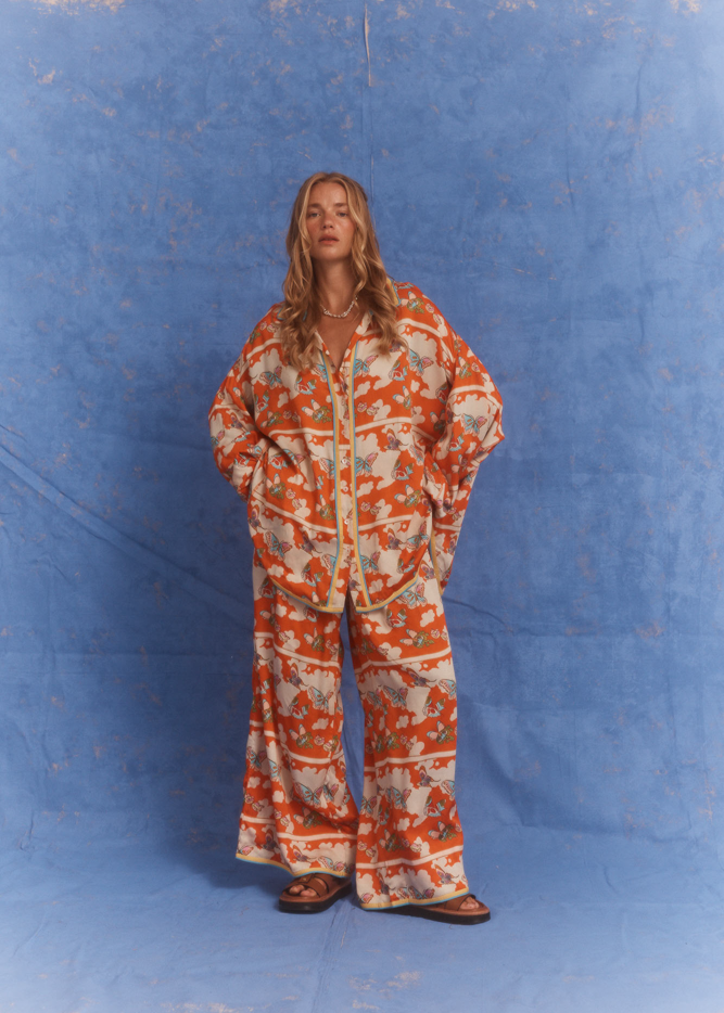 Model wearing Kinga Csilla Farfalla Chalm Shirt and Jessi Pant in bold orange butterfly print matching co-ord set.