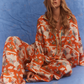 Kinga Csilla Farfalla Jessi Pant in orange butterfly print, relaxed wide-leg women’s pants styled with matching Farfalla Chalm Shirt, model seated against blue backdrop.