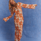 Model posing in the Kinga Csilla Farfalla Olive Dress against a blue studio backdrop, showing its bold orange floral and butterfly print maxi design with flared sleeves
