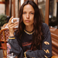 Close-up of model wearing the Kinga Csilla Love Potion Roses Tee in stonewashed black oversized long sleeve, holding a coffee at a Paris café. Sustainable bohemian street style.