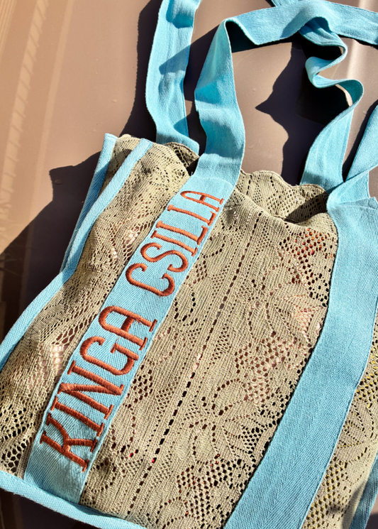 Kinga Csilla Rainy Lace KC Shoulder Bag in sage lace with aqua straps and orange logo embroidery, artisanal bohemian tote bag photographed in sunlight.