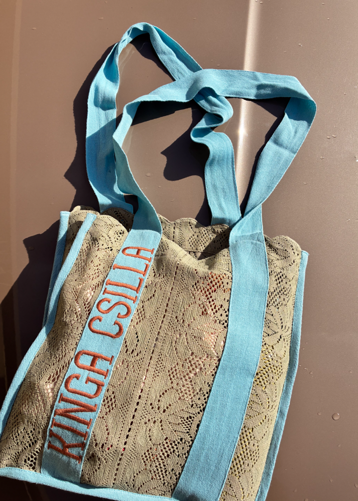 Kinga Csilla Rainy Lace KC Shoulder Bag flatlay on neutral background, featuring aqua blue straps, embroidered logo, and sage lace body detail.