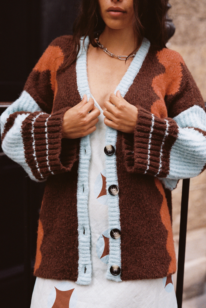 Close-up of model wearing the Kinga Csilla Surf Citta Cardigan in brown, orange and blue over the Aquarius Slip Dress with retro geometric print.