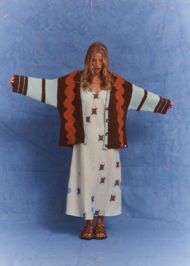 Model wearing the Kinga Csilla Surf Citta Cardigan in retro wave pattern with wide sleeves, styled over the Aquarius Slip Dress with geometric print.