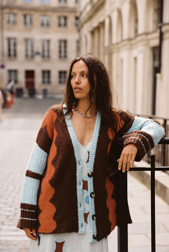 Model wearing the Kinga Csilla Surf Citta Cardigan in brown, orange and baby blue — oversized chunky knit styled over a Aquarius Slip Dress, shot in a European street setting.